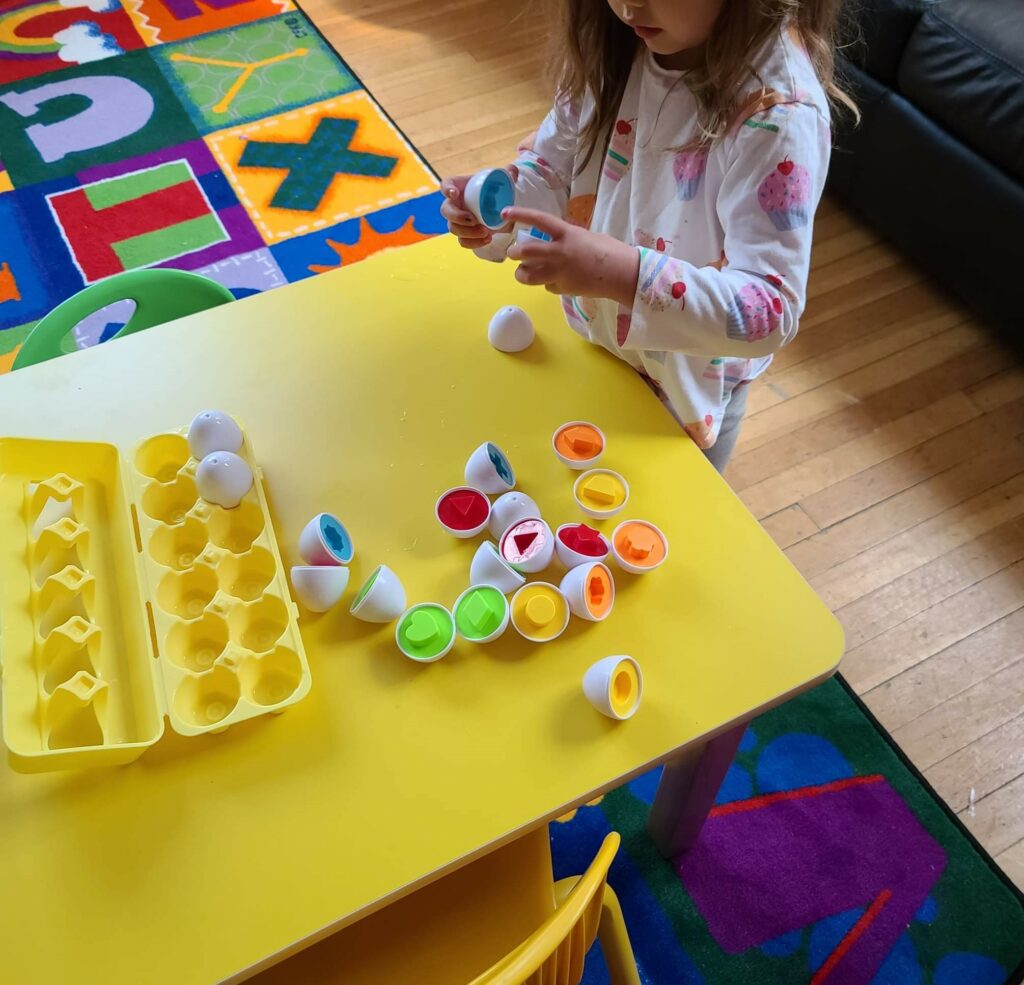 Child playing with toy eggs on table 